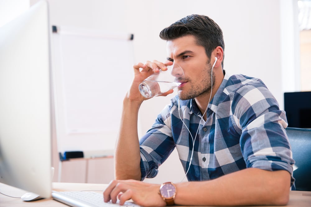 Man in a flannel typing on a computer. 